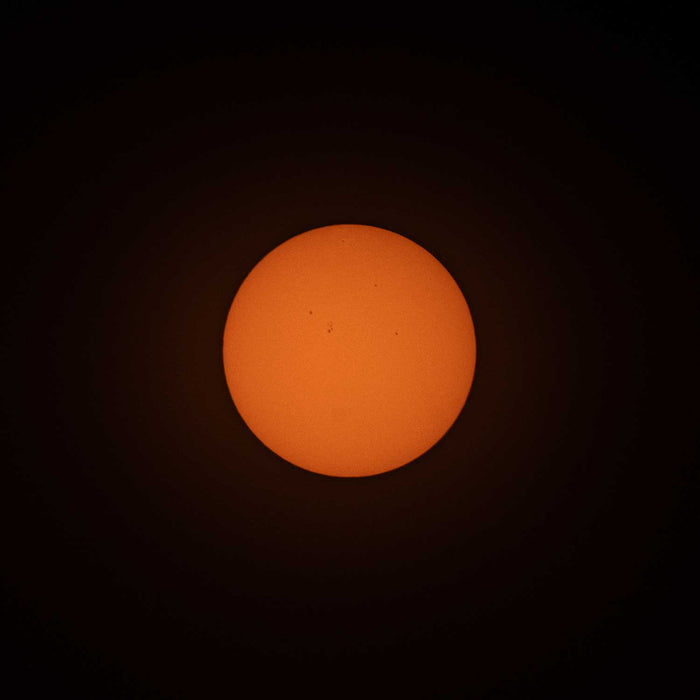 A photo of the sun, taken with ES-FLAR80640CF-iEXOS-100, showing the orange-colored sun with sunspots scattered across the visible surface of the sun